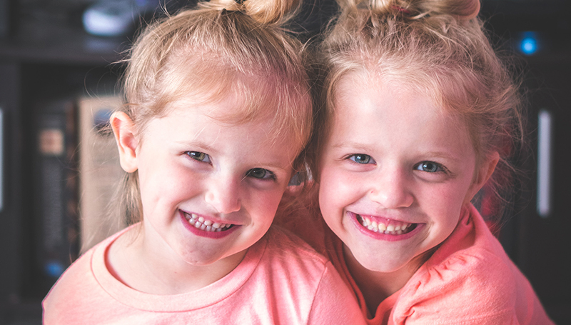 duas meninas de olhos azuis com um sorriso saudável